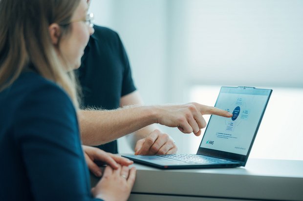 Zwei Projektmitarbeitende besprechen auf einem Laptop die grafische Auswertung der KI-gestützten Pharma-Newsanalyse.