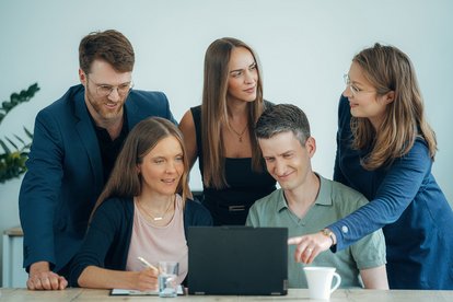 hms-miteinander-gemeinsame-projektarbeit Fünf HMS-Mitarbeitende arbeiten gemeinsam an einer Lösung und besprechen Inhalte an einem Laptop.